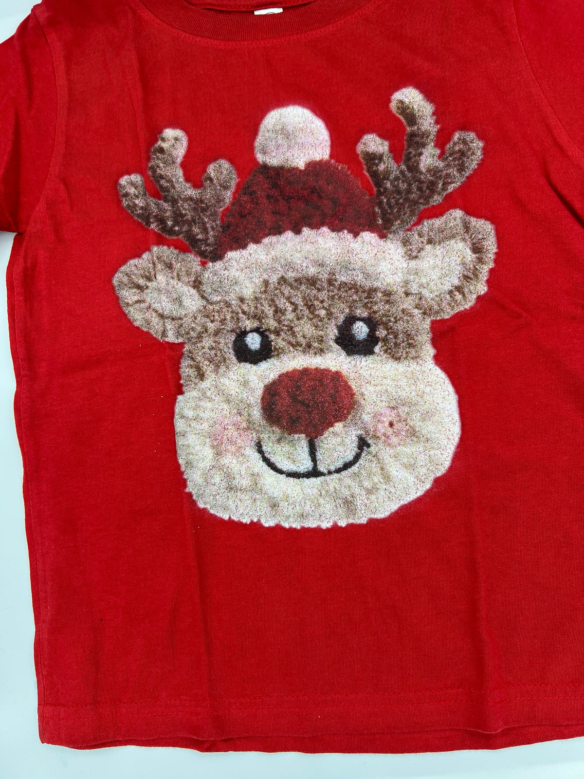 Nannette's Online Designs red short sleeve t-shirt featuring a textured reindeer graphic wearing a Santa hat
