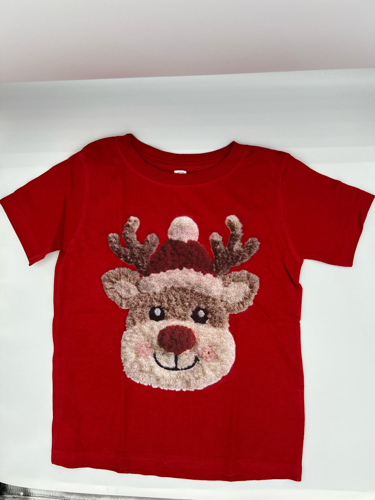 Nannette's Online Designs red short sleeve t-shirt with a textured reindeer graphic wearing a festive Santa hat.
