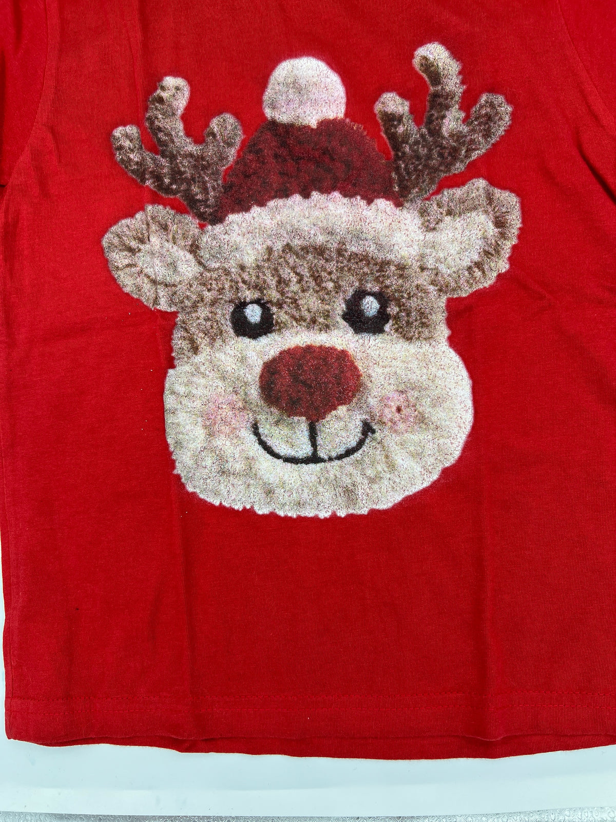 Nannette's Online Designs red short sleeve t-shirt featuring a textured reindeer graphic with a festive Santa hat.