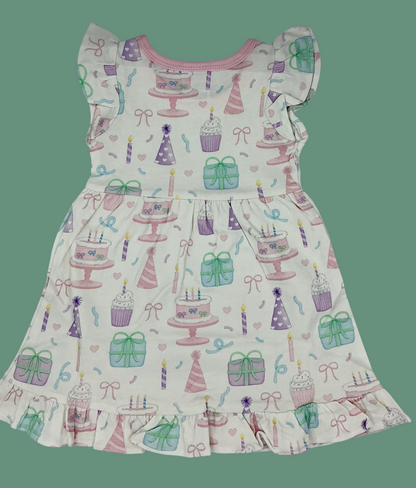 Nannette's Online Designs toddler girl birthday dress with pastel cake, cupcake, and gift print and ruffled hem.