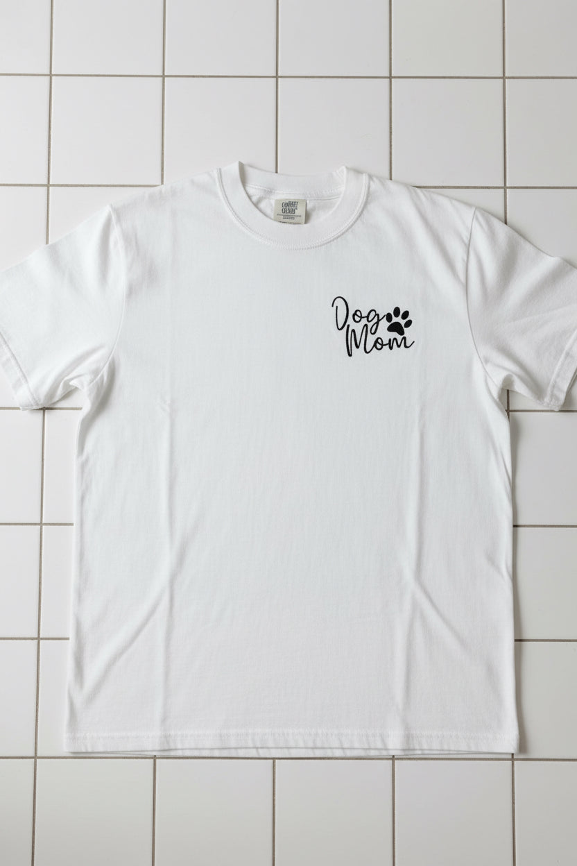 Nannette's Online Designs white cotton t-shirt featuring minimalist black Dog Mom embroidery with a paw print.